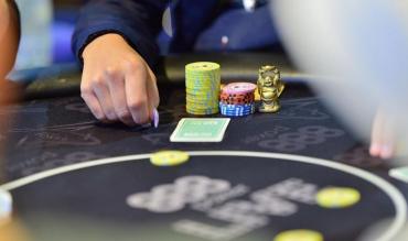 Mesa de poker com fichas e a mão de um jogador
